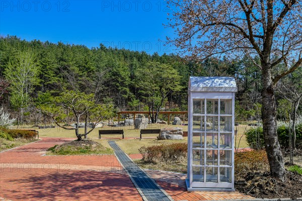 White wooden box with square windows under tree in public park