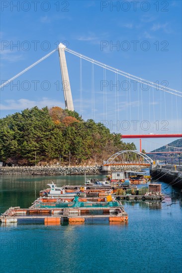 Seascape of seaport with storage barges moored to pier and bridge in background in South Korea