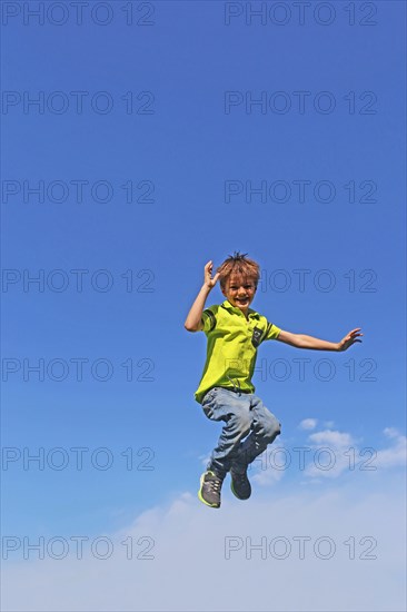 Symbolic image: Boy jumping into the air, blue sky in the background