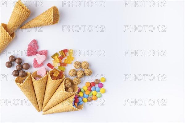 Various sweets in and out of ice-cream cones on a white background, copy room