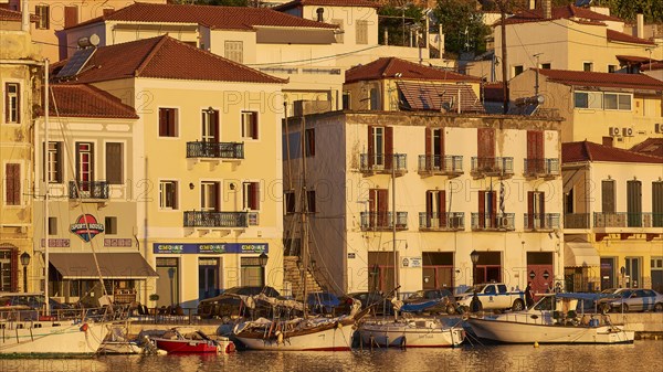 The last rays of sunshine of the day cosily illuminate the waterfront with cafes and boats, Gythio, Mani, Peloponnese, Greece, Europe