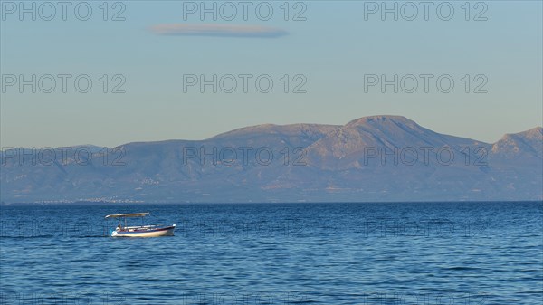 Lonely boat on the wide blue sea with mountains in the background and clear sky, Gythio, Mani, Peloponnese, Greece, Europe