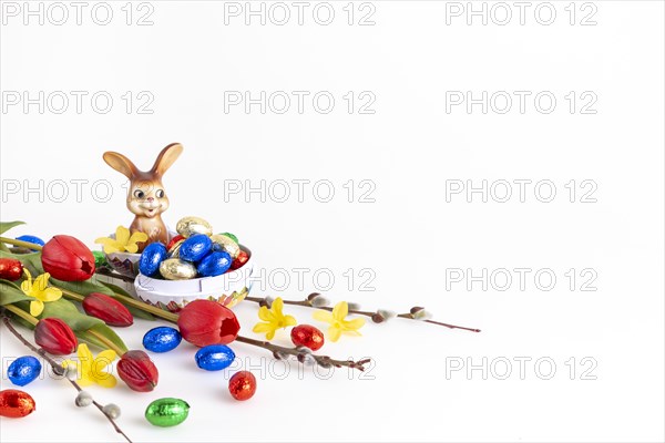 Colourful Easter decoration with an Easter bunny and a variety of chocolate eggs, white background, copy room