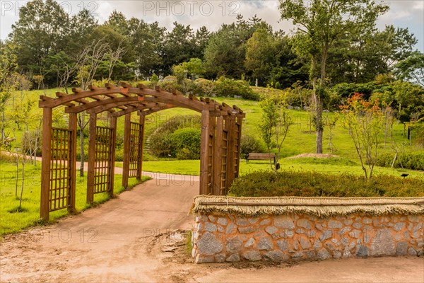 Wooden trellises over concrete walkway in urban park on sunny day in South Korea