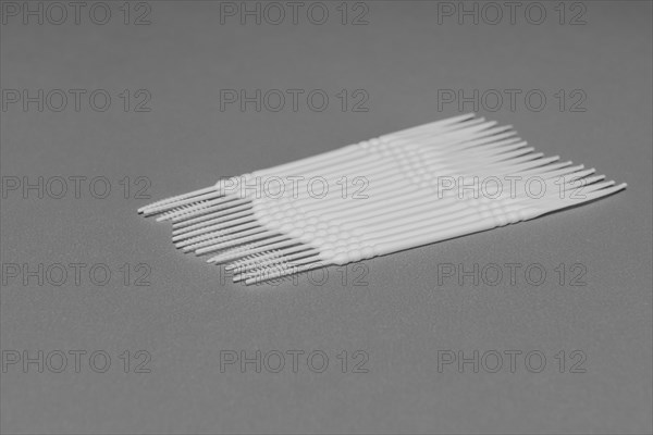 Black and white of plastic flossing picks on gray background