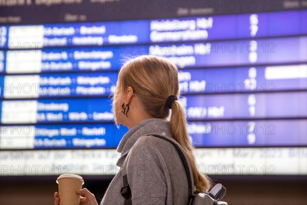 Young woman looking at the scoreboard in a railway station