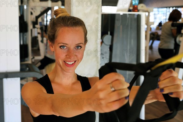 Young woman doing TRX training in the gym, (Neuhofen, Rhineland-Palatinate)