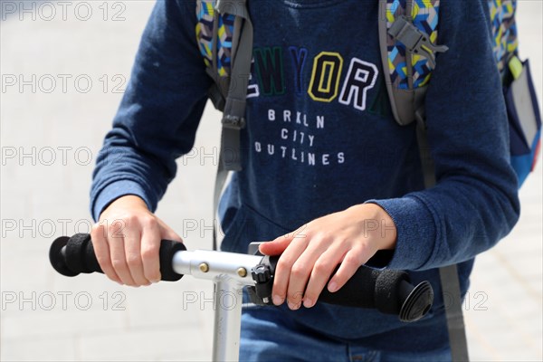 Symbolic image: Schoolchild with scooter on the way to school