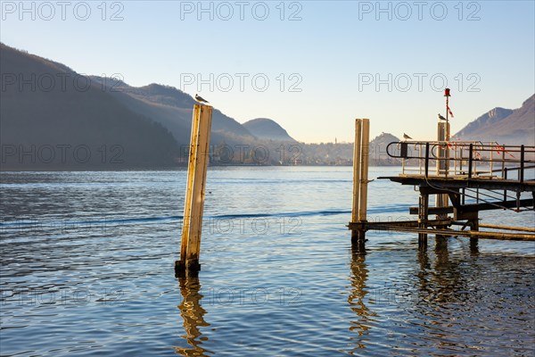 Jetty on Lake Lugano with Mountain and City in a Sunny Day with Clear Sky in Porto Ceresio, Lombardy, Italy, Europe