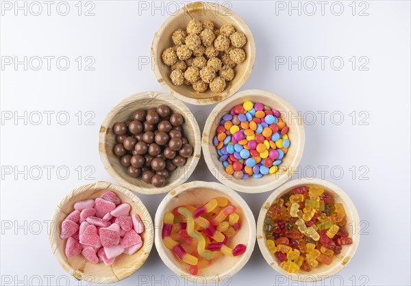 Various sweets arranged in wooden bowls on a white background