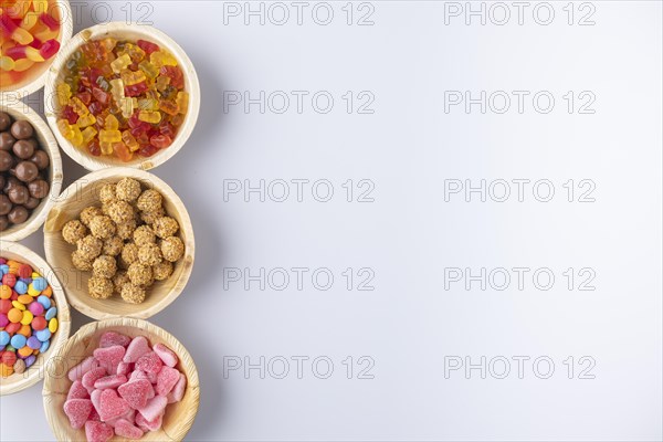 Colourful sweets in bowls with lots of free space on a white background