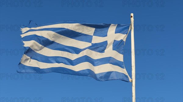 The Greek flag fluttering in the wind on a mast, against a clear blue sky, Gythio, Mani, Peloponnese, Greece, Europe