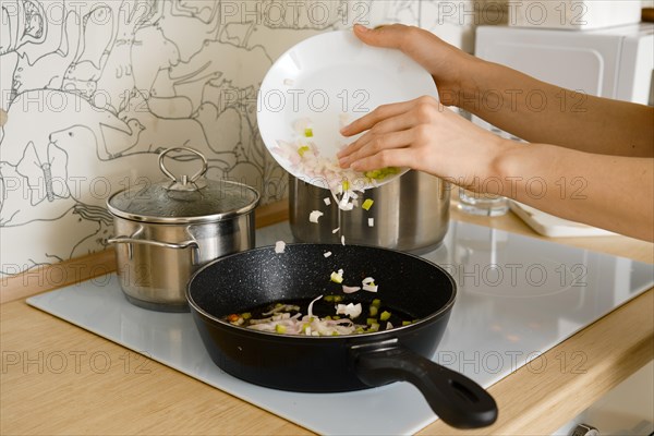 Closeup view of throwing chopped onion and celery to a frying pan