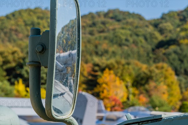 Closeup of external mirror on military vehicle on display in public park with blurred background