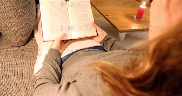 Woman comfortably reading a book on the sofa