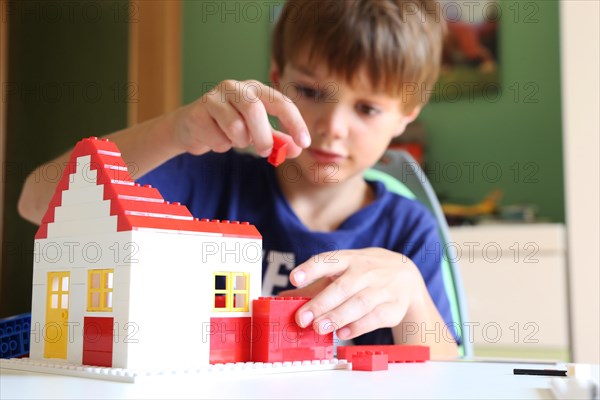 Symbolic image: Boy builds a house with building blocks