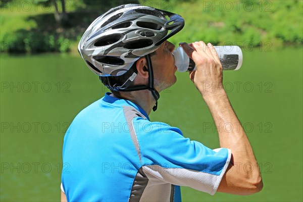 Symbolic image: Mountain biker taking a break at a lake (Edenkoben Valley in the Palatinate Forest)