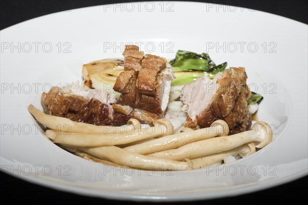 Crispy fried pork belly on Japanese udon noodles, with briefly braised pak choi and enoki mushrooms, food photography