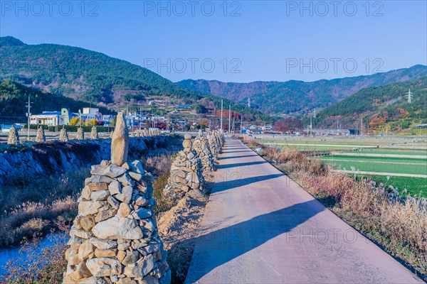 Row of cairn beside single lane concrete road in rural community in South Korea