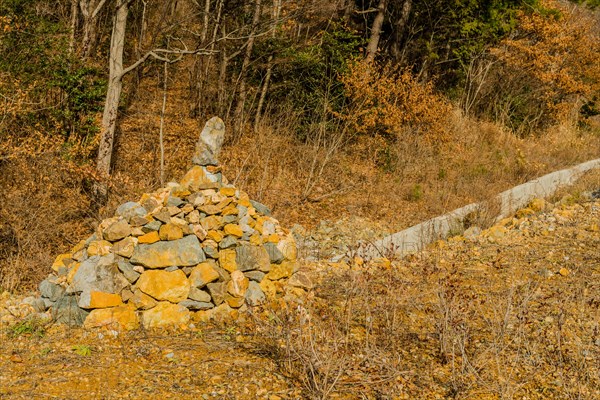 Stack of stones on hillside in wilderness countryside with trees in background
