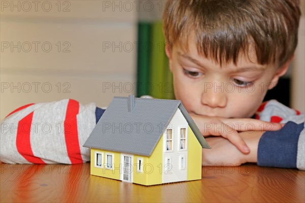 Boy looks longingly at a model house