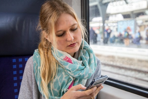 Young woman on the train looks at her smartphone