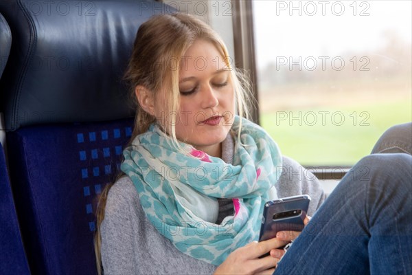 Young woman on the train looks at her smartphone