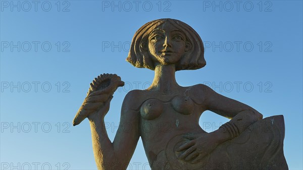 A female statue holding up a palm, mermaid, against a clear blue sky, Gythio, Mani, Peloponnese, Greece, Europe