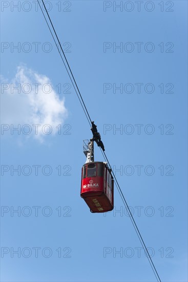Red cable car gondola hanging on a rope against a clear blue sky with few clouds, Balea Cascada cable car station, Transfogarasan High Road, Transfagarasan, TransfagaraÈ™an, FagaraÈ™ Mountains, Fagaras, Transylvania, Transylvania, Transylvania, Ardeal, Transilvania, Carpathians, Romania, Europe