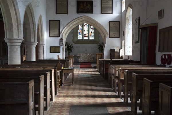 View past wooden pews to chancel arch and altar in sanctuary in the church at Milton Lilbourne, Wiltshire, England. The church was renovated in 1875, overseen by Reverend John Henry Gale vicar from 1846 until 1893