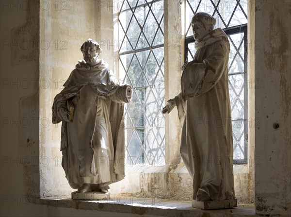 Two statues of monks or saints standing by a window inside village parish church at Dauntsey, Wiltshire, England, UK