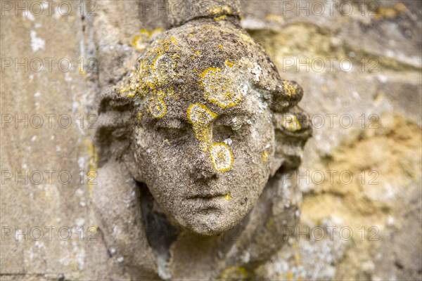 Carved stone head and face weathered figure on exterior of Brantham church Suffolk, England, UK