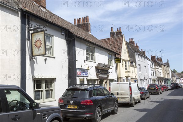 Historic buildings in main street of Bruton, Somerset, England, UK, The Sun Inn public house sign