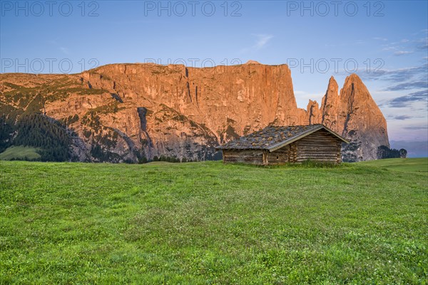 Alpine hut in front of Schlern, sunrise, blue sky with clouds, Seiser Alm, Dolomites, South Tyrol