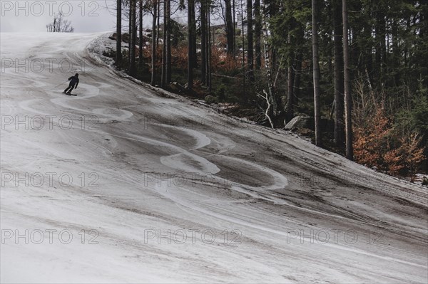 A skier skis on an artificially snow-covered and dirty slope, taken on a ski slope in the Jizera Mountains ski resort near Albrechtice v Jizerskych Horach, 05.02.2024. The Czech low mountain range with its ski resort is affected by increasingly warmer and shorter winters