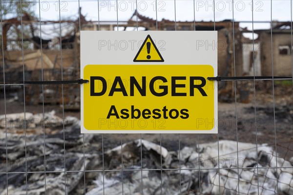 Industrial building destroyed by fire, Hatcher Components Ltd, Parham airfield, Suffolk, England, UK, Danger Asbestos sign