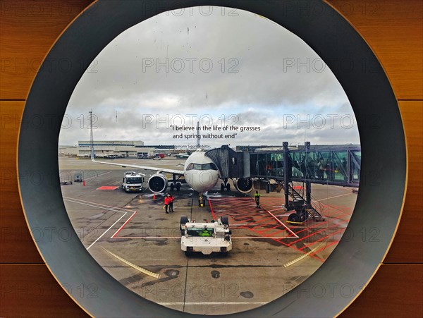 View from a round window of an aeroplane on the tarmac with a printed phrase at Keflavik International Airport, Iceland, Europe