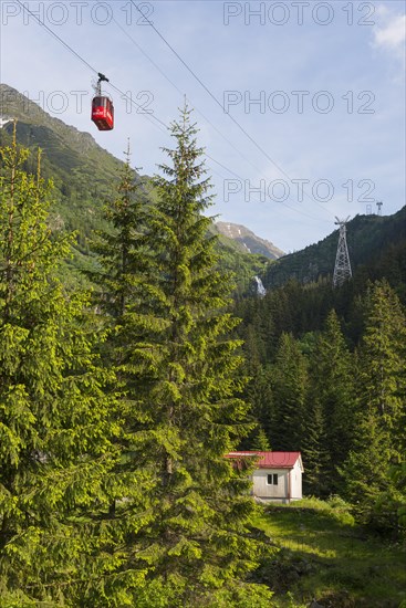 Small cable car gondola crosses a picturesque mountain landscape with fir trees and a small hut and the Balea waterfall, Balea Cascada cable car station, Transfogarasan High Road, Transfagarasan, TransfagaraÈ™an, FagaraÈ™ Mountains, Fagaras, Transylvania, Transylvania, Transylvania, Ardeal, Transylvania, Carpathians, Romania, Europe