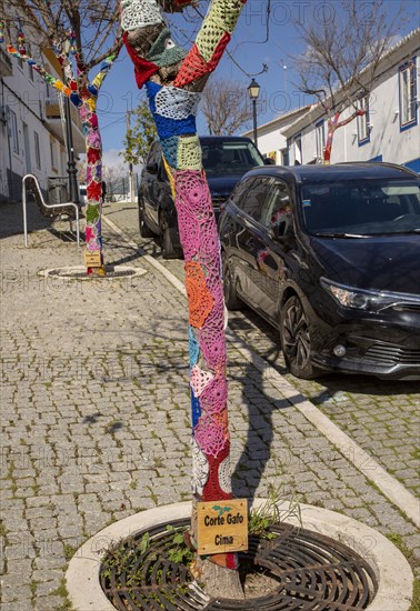 Star shaped wool crochet woollen pattern around tree trunk in street of village Mertola, Portugal, Europe
