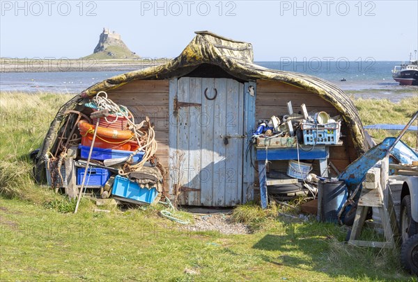 Old upturned boat used as store shed for fishing equipment, Holy Island, Lindisfarne, Northumberland, England, UK