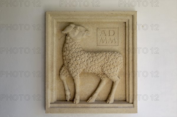 Millennium sculpture Sebastian Brooke carved relief of lamb in porch of Saint John the Baptist church, Mildenhall, Wiltshire, England, UK