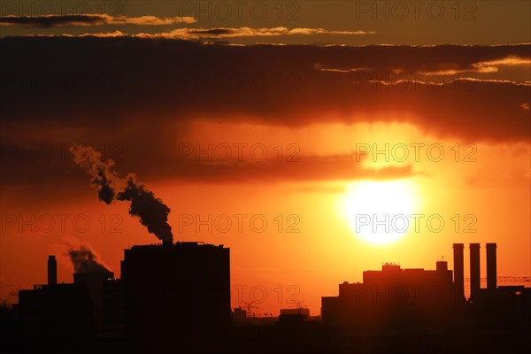 Plumes of smoke from the chimneys of a combined heat and power plant and a waste-to-energy plant at sunset, Berlin, 26/04/2021