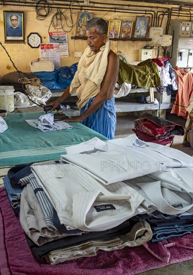 A man irons shirts with an antique iron at Dhobi Khana Public Laundry, Fort Kochi, Cochin, Kerala, India, Asia