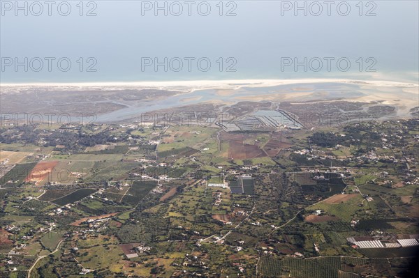 Aerial view of coastline near Faro, Algarve, Portugal showing settlements on coastal plain and offshore sand banks with sandy beaches running along the coast