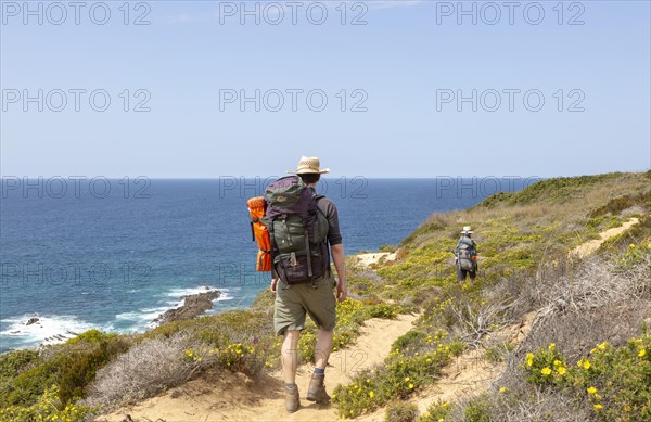 Two people walking the cliff top coastal long distance footpath trail, The Fisherman's Walk or Ruta Vicentina, near Odeceixe, Algarve, Portugal, Southern Europe, Europe
