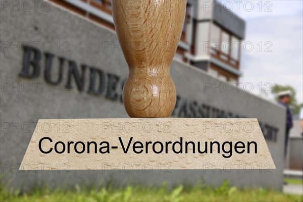 Symbolic image of the constitutional complaint against corona regulations: In the foreground a stamp, in the background the Federal Constitutional Court in Karlsruhe