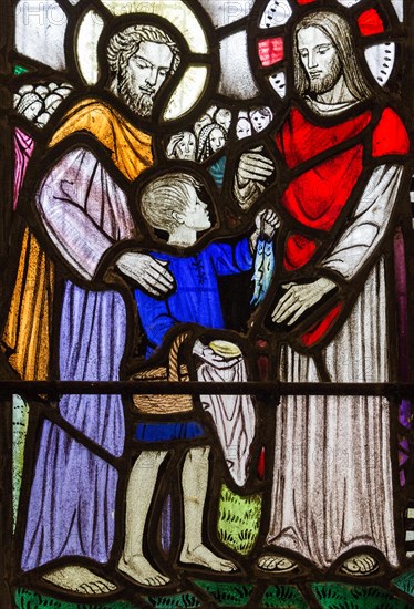 Church of Saint Andrew, Little Glemham, Suffolk, England, UK stained glass window detail of boy offering fish to feed the five thousand 1929 by Margaret Edith Aldrich Rope (1891-1988)