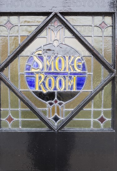 Close-up of stained glass window old vintage pub sign for Smoke Room, The Parrot public house, Aldringham, Suffolk, England, UK