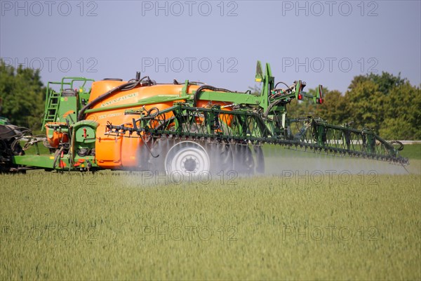 A farmer drives his tractor with a crop protection sprayer across his wheat field to combat brown rust and mildew (Hockenheim, Baden-Wuerttemberg)