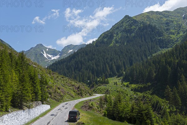 Road leading through a picturesque mountain landscape with lush greenery and clear blue skies, Mountain Road, Transfogarasan High Road, Transfagarasan, TransfagaraÈ™an, FagaraÈ™ Mountains, Fagaras, Transylvania, Transylvania, Transylvania, Ardeal, Transilvania, Carpathians, Romania, Europe